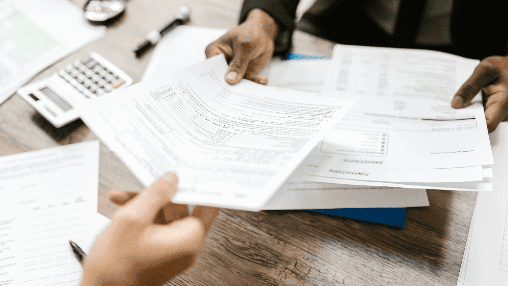 Close-up of hands handling tax forms and financial documents.