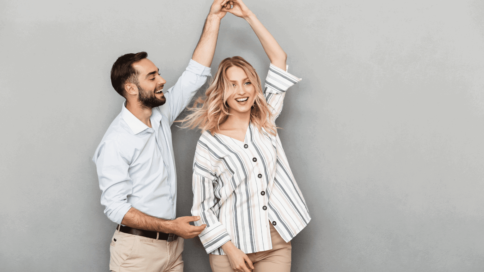 Smiling couple dancing and having fun indoors.