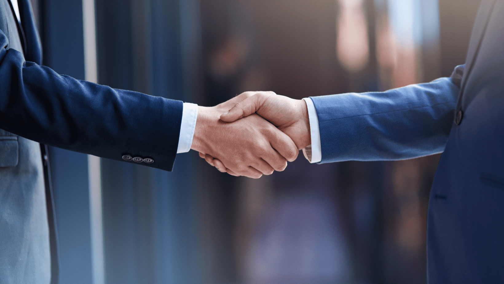 A handshake between two business professionals in formal suits.