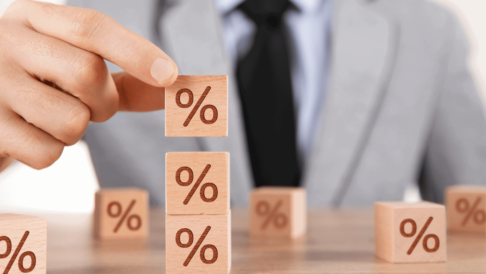 Hand placing wooden blocks with percentage symbols on a table.