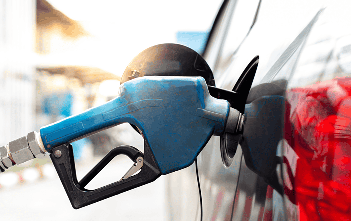 Close-up of a blue fuel pump nozzle inserted into a vehicle's fuel tank.