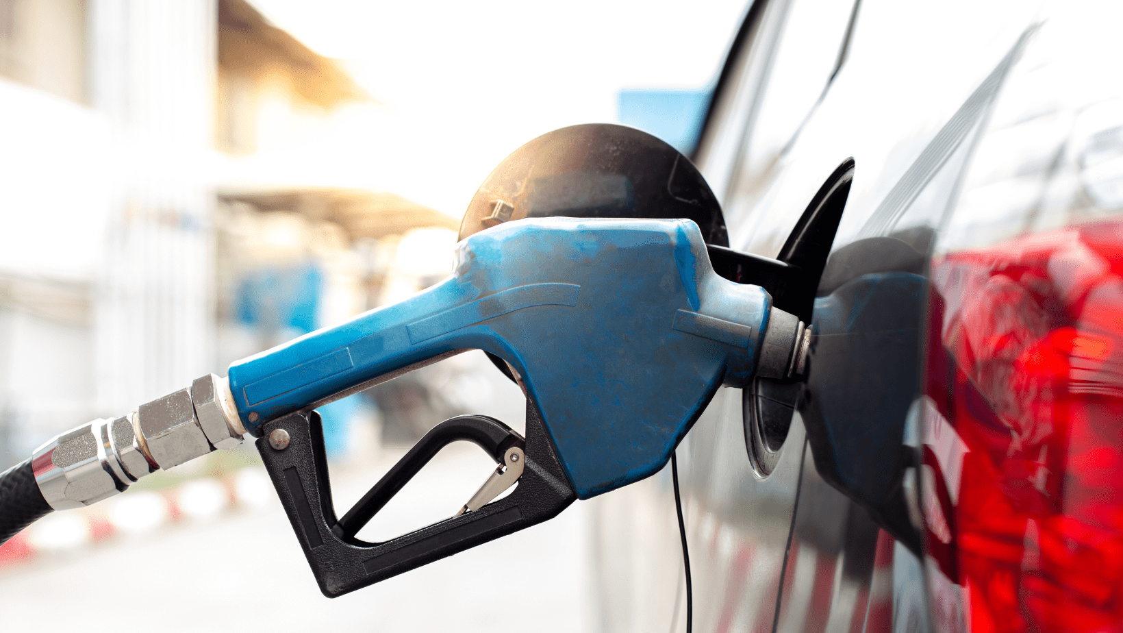 Close-up of a blue fuel pump nozzle inserted into a vehicle's fuel tank.