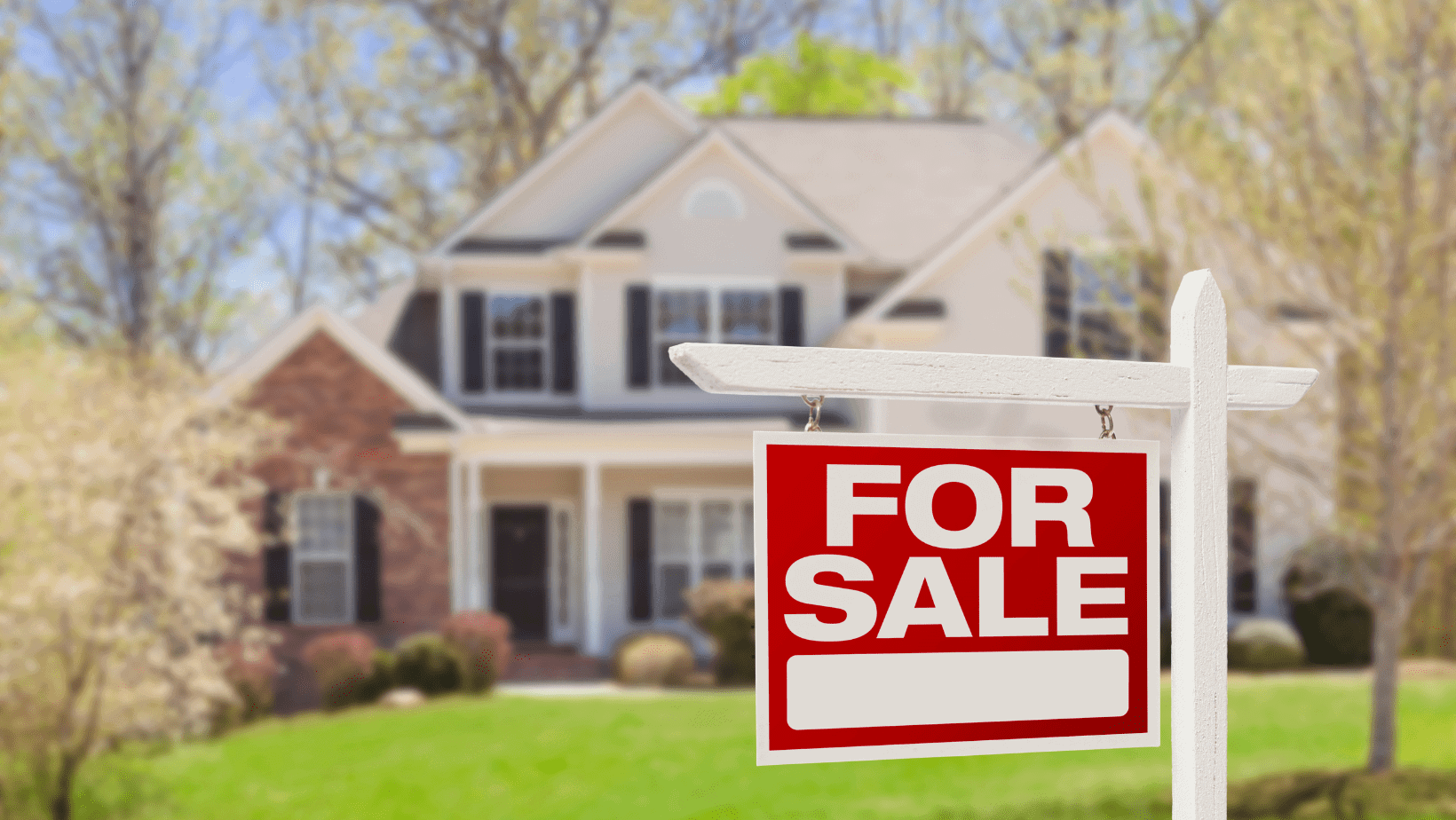House with a "For Sale" sign in the yard.