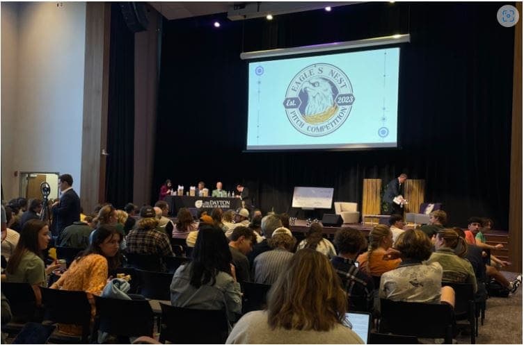 Community meeting with audience and panel on stage in auditorium.