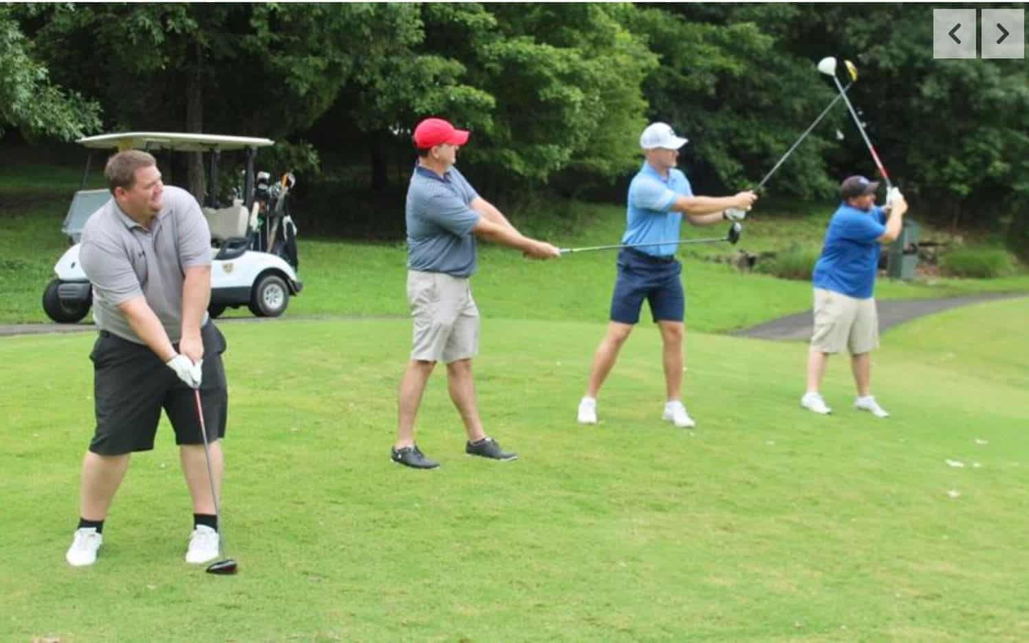 Golfers practicing swings on a lush green course with a golf cart in the background.