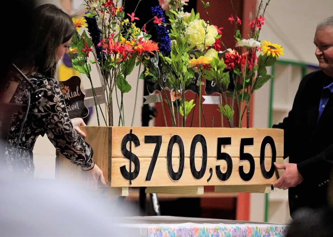Woman presenting a large donation check of $700,550 at a charity event.