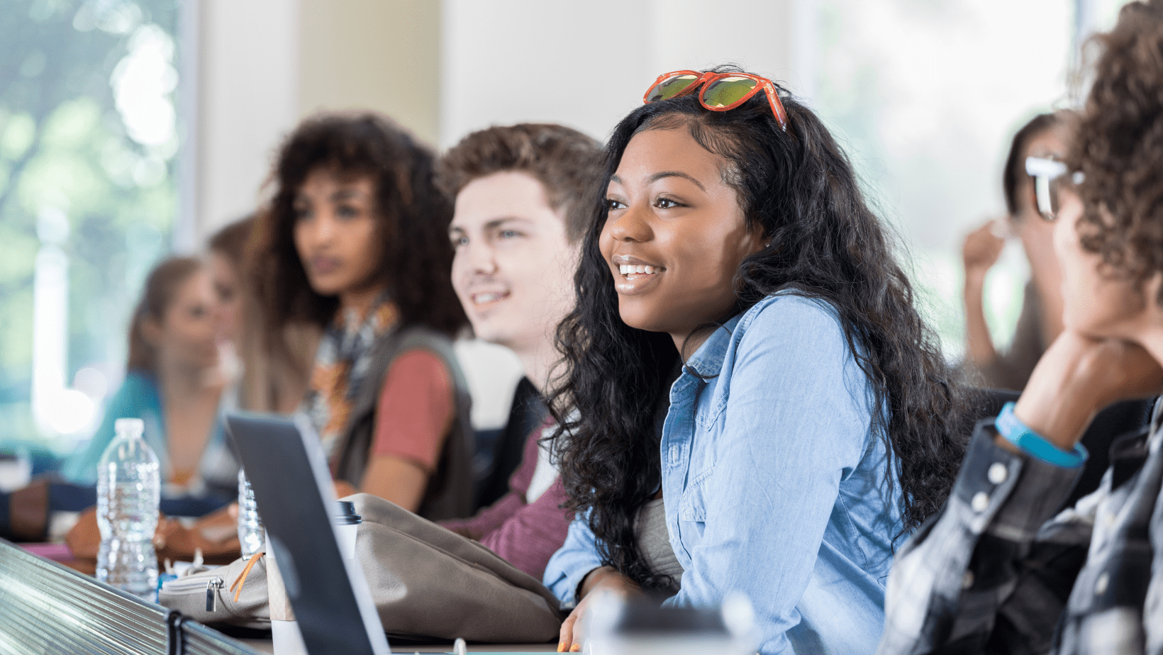 Students sitting at desks in a classroom, engaging and smiling.